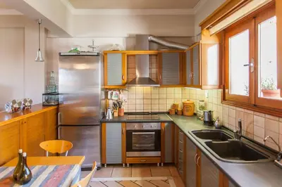 a kitchen with wooden cabinets and a stainless steel refrigerator at Sea view maisonette in Chania Town