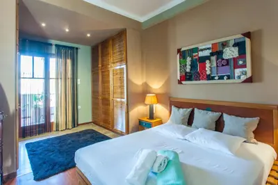 a bedroom with a large white bed with a blue rug at Sea view maisonette in Chania Town
