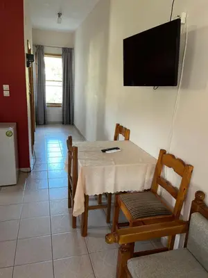 a dining room with a table and a television on the wall at Mediterranean Sea Down Floor in Palaiochóra