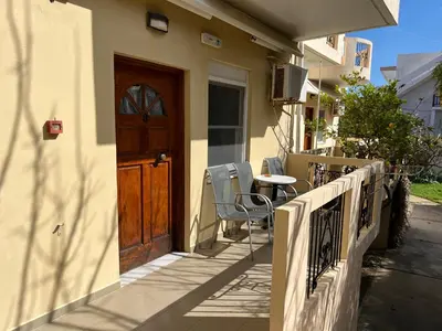 a balcony with a wooden door and a table and chairs at Mediterranean Sea Down Floor in Palaiochóra