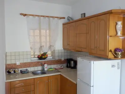 a kitchen with wooden cabinets and a white refrigerator at Charisma Apartment in Plataniás