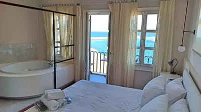 a bedroom with a tub and a bed with a view at Hotel Amphora in Chania Town
