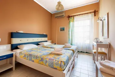 a bedroom with two beds and a window at Rea Hotel in Palaiochóra