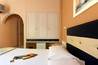 a bedroom with a bed and a cabinet at Rea Hotel in Palaiochóra