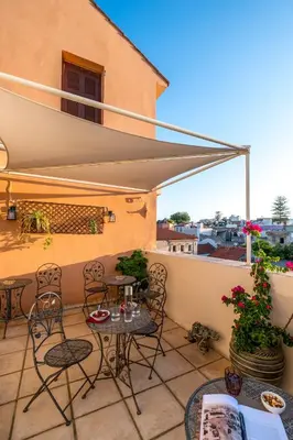 a patio with chairs and tables and an umbrella at Santa Elena Boutique Rooms in Chania Town