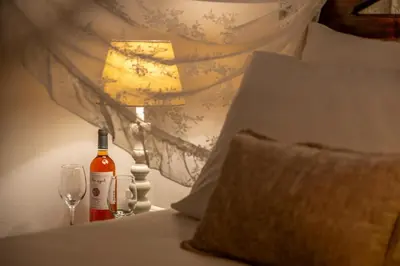 a bottle of wine and a lamp on a bed at Santa Elena Boutique Rooms in Chania Town