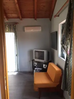 a living room with a yellow chair and a television at Kavros House in Arménoi