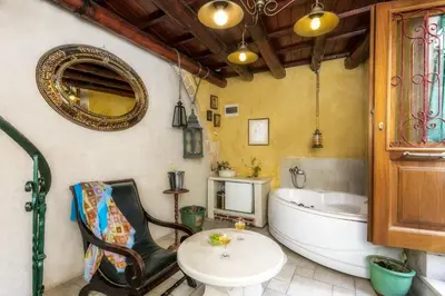 a bathroom with a tub and a table and a chair at Ifigenia Traditional Rooms & Maisonettes in Chania Town