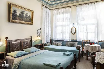 a bedroom with two beds and a table and windows at Pension Lena in Chania Town