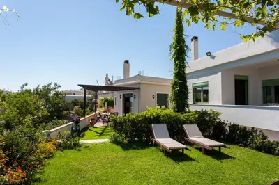 a house with two chairs in the yard at Chania Sea View Summer House in Kalamaki Chanion