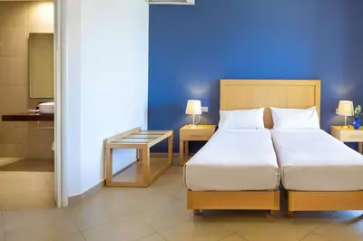 a bedroom with a bed and a blue wall at Elena Beach Hotel in Kissamos