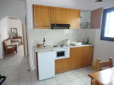 a kitchen with wooden cabinets and a white stove top oven at Flisvos Apartments in Frangokastello
