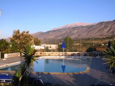 a large swimming pool with mountains in the background at Flisvos Apartments in Frangokastello