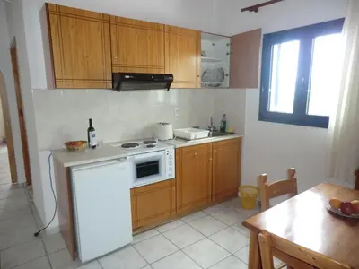 a kitchen with a white refrigerator and wooden cabinets at Flisvos Apartments in Frangokastello