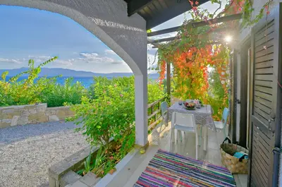 a table and chairs on a porch with a view of the ocean at Villas Vista Del Mar in Kissamos