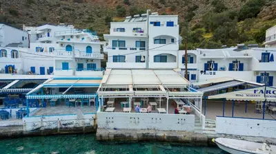 a boat in the water next to a group of buildings at Kyma in Loutro