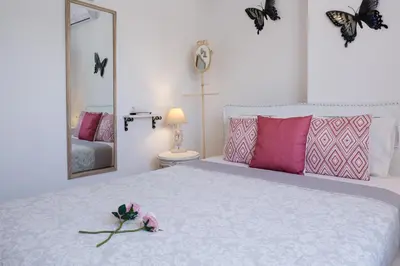 a bedroom with a bed with pink pillows and a mirror at EvaEle Luxury Boutique in Kissamos