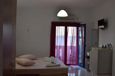 a bedroom with a bed and a window with red curtains at Paralia guest house in Agia Roumeli