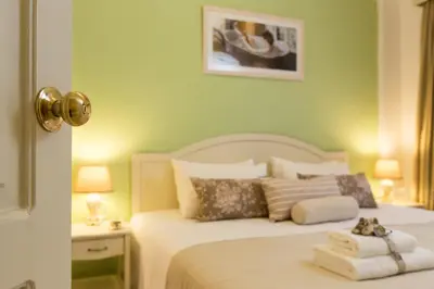a bedroom with a white bed with green walls at Agrimia Holiday Apartments in Plataniás