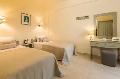 a hotel room with two beds and a mirror at Agrimia Holiday Apartments in Plataniás
