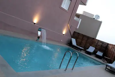 a swimming pool with a water fountain in a building at Mithos Premium Rooms in Agia Marina Nea Kydonias