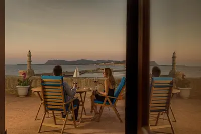 a group of people sitting at a table watching the ocean at Revellino del Porto, Historic Residence in Chania Town