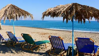 four chairs and an umbrella on a beach at Stavros Villas&Apartments in Gerani Chanion