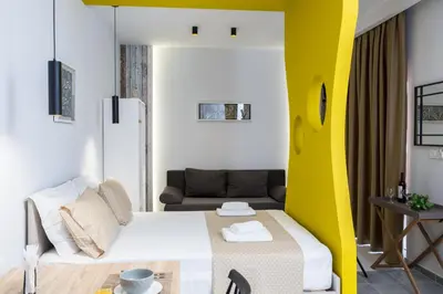 a small room with a bed and a yellow wall at NK Apartments in Falasarna