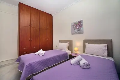 two beds in a room with purple sheets at Aristea's Apartment 1st Floor in Chania Town