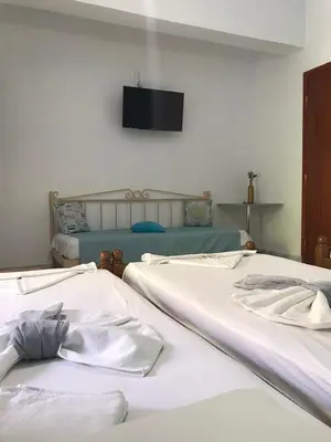 two beds in a room with a tv on the wall at Panorama Rooms in Agia Roumeli