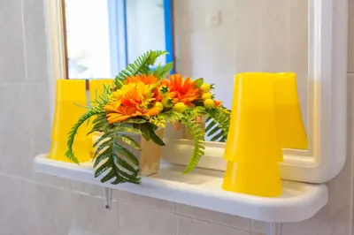 a bathroom shelf with a mirror and a bouquet of flowers at Panorama Rooms in Agia Roumeli