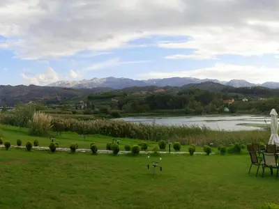 a green field with a river and mountains in the background at Villa Oasis in Galatás