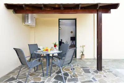 a patio with a table and chairs on a stone floor at Feels like home in Chania Town