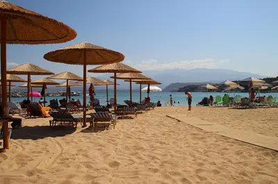 a beach with chairs and umbrellas and people on the beach at Feels like home in Chania Town
