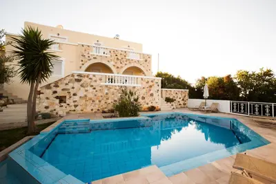 a swimming pool in front of a house at Ilios Village in Stalos