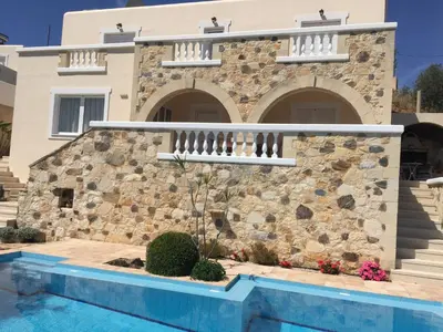 a house with a stone wall and a swimming pool at Ilios Village in Stalos