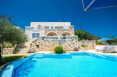 a villa with a swimming pool in front of a house at Ilios Village in Stalos