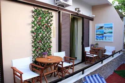 a balcony with wooden tables and chairs and a plant at Your Home in Kato Daratso