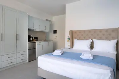a bedroom with a large bed and a kitchen at Molos Apartments in Loutro