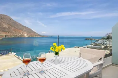 a table with two glasses of wine and flowers on a balcony at Molos Apartments in Loutro