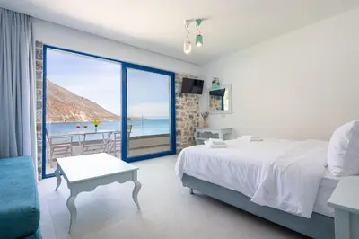 a bedroom with a bed and a view of the ocean at Molos Apartments in Loutro
