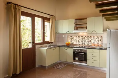 a kitchen with white cabinets and a sink and a refrigerator at Filio House in Stalos