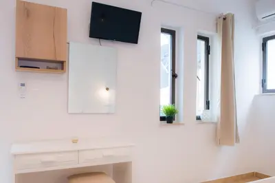a white room with a tv on a wall with windows at Stellar Apartments I in Plataniás