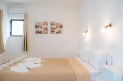 a white bedroom with a bed with white pillows at Stellar Apartments I in Plataniás