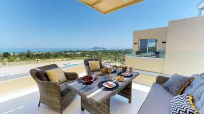 a living room with a table and chairs and a view of the ocean at Liberty & Freedom Luxury Villa-heated pool in Plataniás
