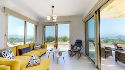a living room with a yellow couch and large windows at Liberty & Freedom Luxury Villa-heated pool in Plataniás