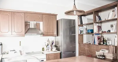 a kitchen with wooden cabinets and a stainless steel refrigerator at Thalassa Old Town Apartment in Chania Town