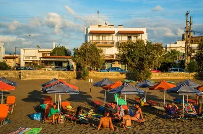 a group of people sitting under umbrellas on a beach at Pal Beach in Palaiochóra