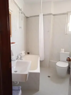 a white bathroom with a sink and a toilet at Pal Beach in Palaiochóra