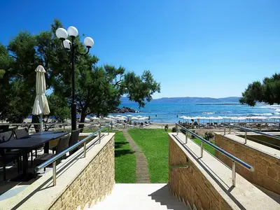 a view of a beach with a table and an umbrella at Molos Bay Hotel in Kissamos